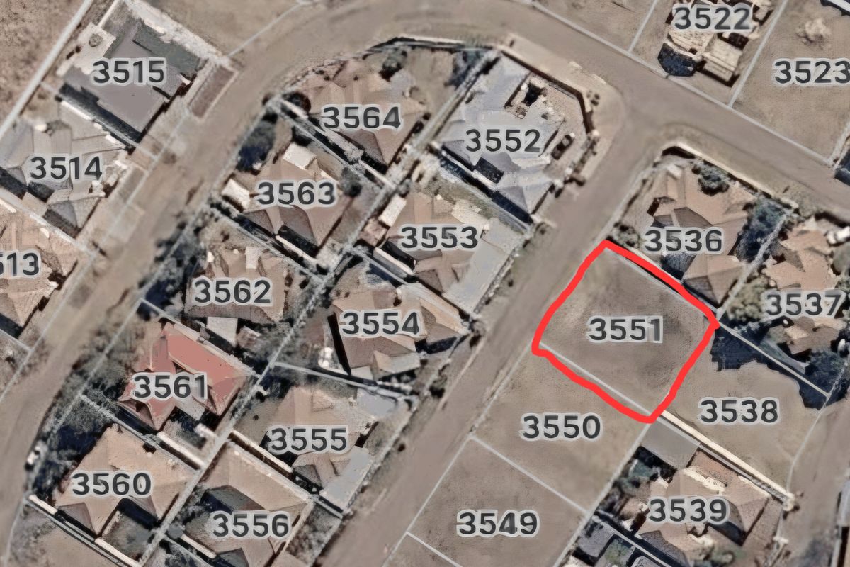 Aerial view of a vacant residential land plot highlighted in red within an established suburban neighborhood.