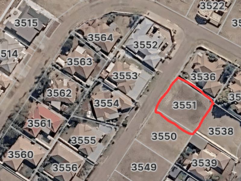 Aerial view of a vacant residential land plot highlighted in red within an established suburban neighborhood.