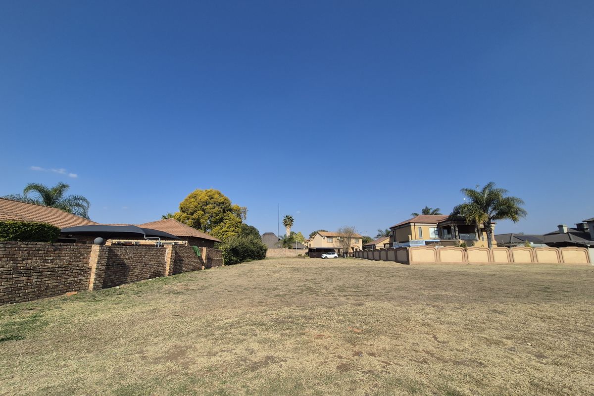 A vacant residential plot featuring a level grass lawn and established boundary walls, situated within an established neighborhood.