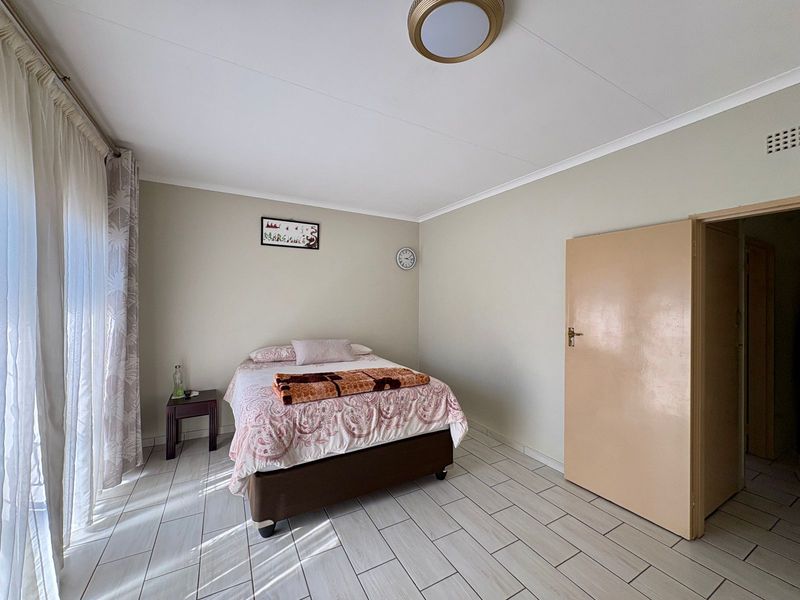 A functional bedroom featuring tiled flooring, neutral wall tones, and a flush mount ceiling light, providing a clean and simple living space.