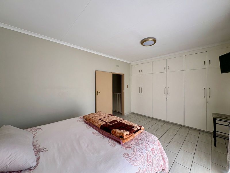 A bedroom featuring tiled flooring, neutral walls, and extensive built-in cupboard storage.