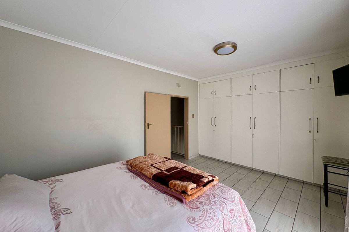 A bedroom featuring tiled flooring, neutral walls, and extensive built-in cupboard storage.