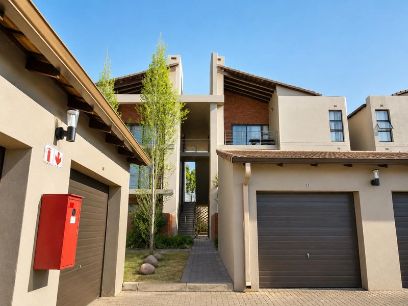 Front view of a modern apartment complex featuring paved driveways, integrated garages, and multi-level residential units with balconies.