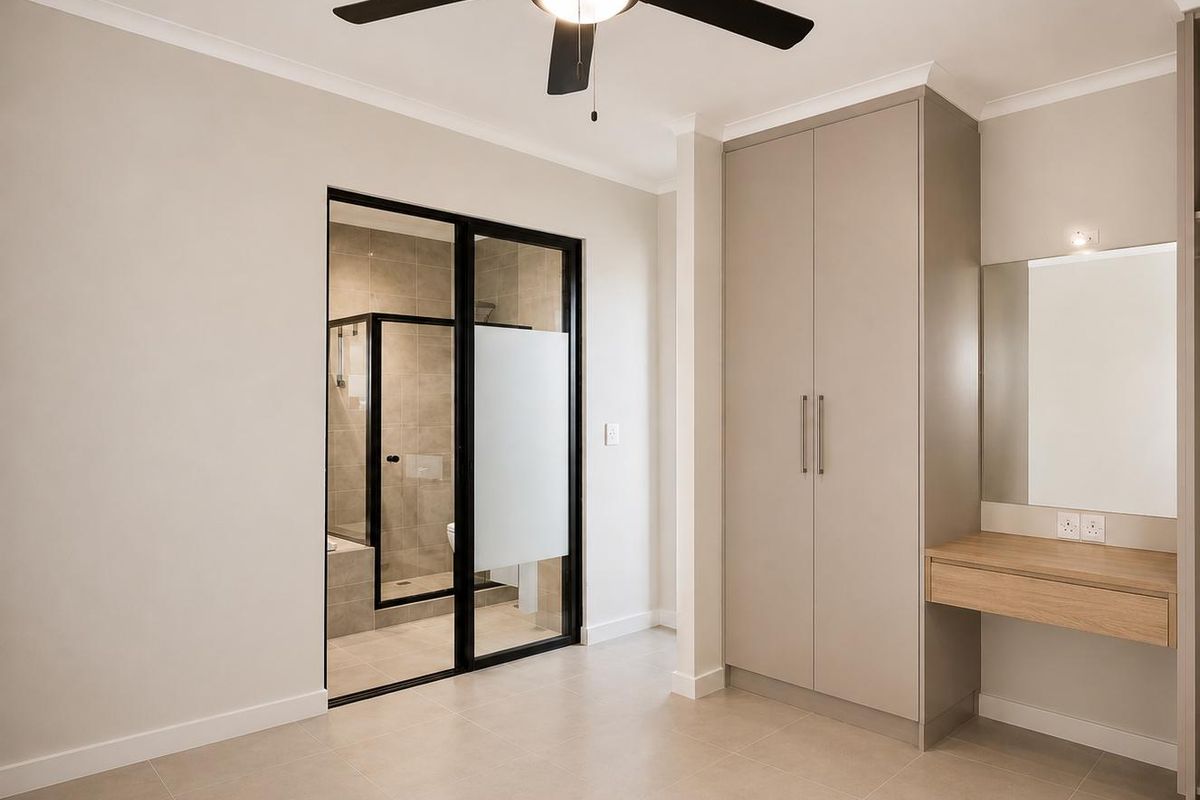 Modern bedroom featuring a built-in wardrobe, floating vanity, ceiling fan, and an en-suite bathroom with a sleek glass partition.