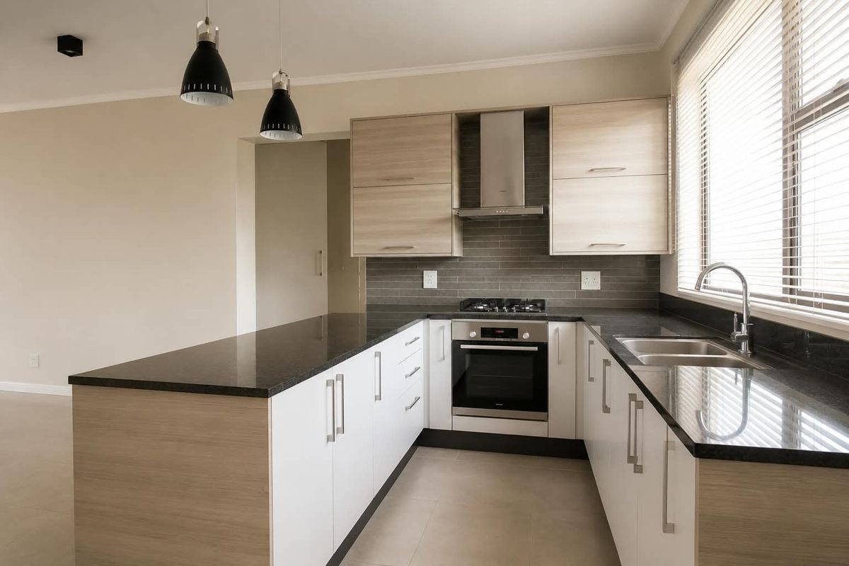 Modern kitchen featuring light wood and white cabinetry, dark granite countertops, built-in oven, gas hob, extractor fan, and a double sink.