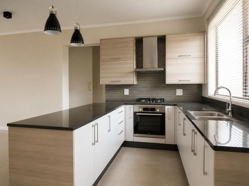 Modern kitchen featuring light wood and white cabinetry, dark granite countertops, built-in oven, gas hob, extractor fan, and a double sink.
