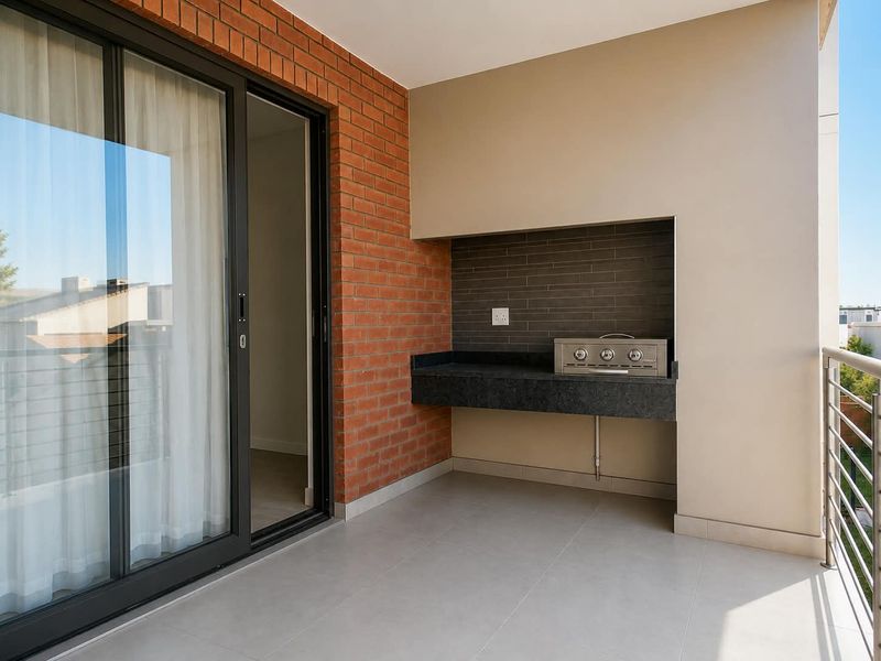 A modern covered balcony featuring a built-in braai with granite countertop, brick accent wall, and sleek metal balustrade, perfect for outdoor entertaining.