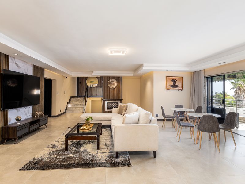 Spacious open-plan living and dining area featuring modern slatted timber wall paneling, marble accents, recessed lighting, and large sliding doors leading to the patio.