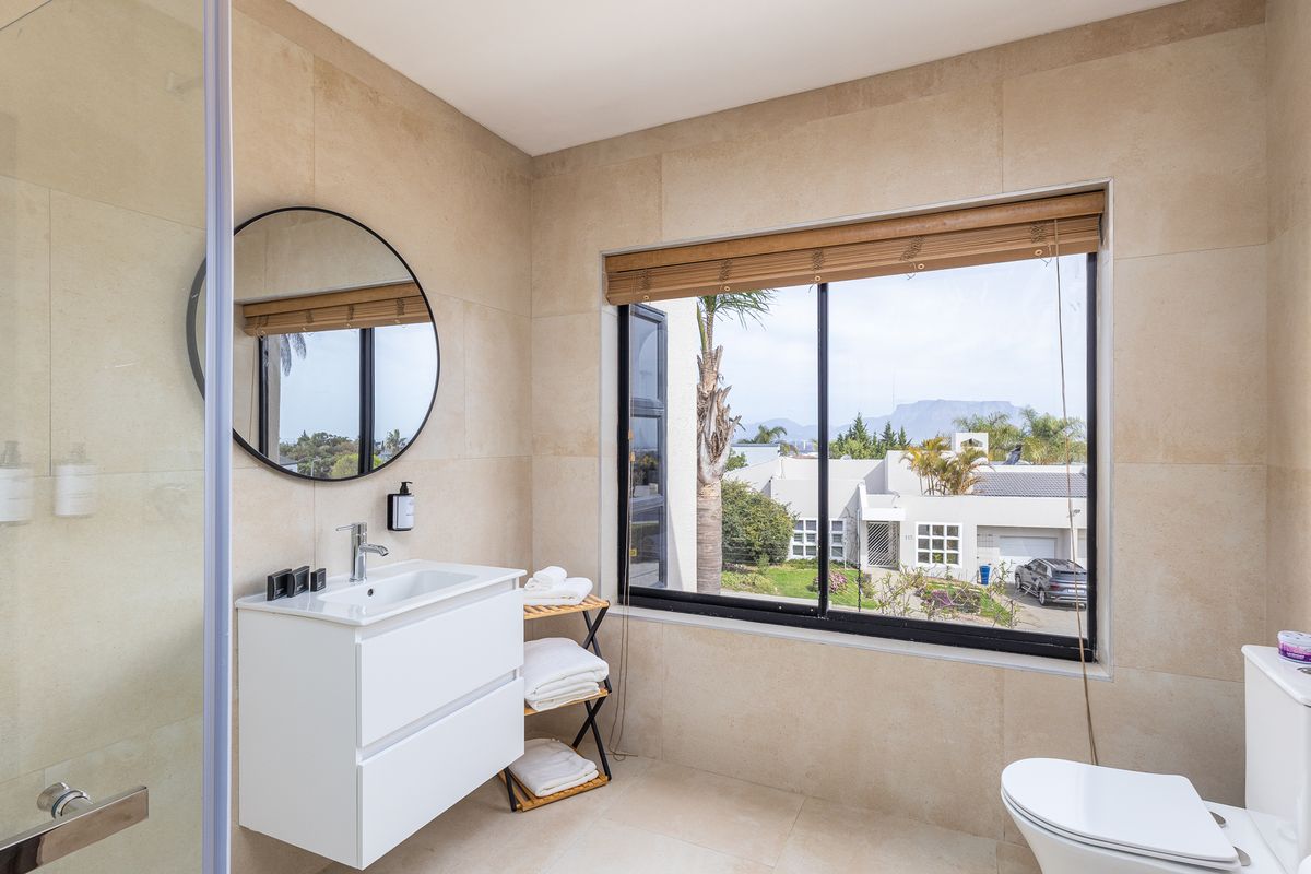 Modern bathroom featuring a wall-mounted vanity, tiled finishes, and a large window with views, creating a bright and functional space.