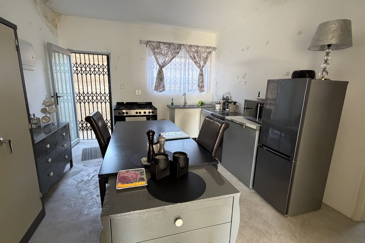 Compact kitchen area featuring a gas stove, sink, and built-in cabinetry, requiring cosmetic updates and ceiling repairs.
