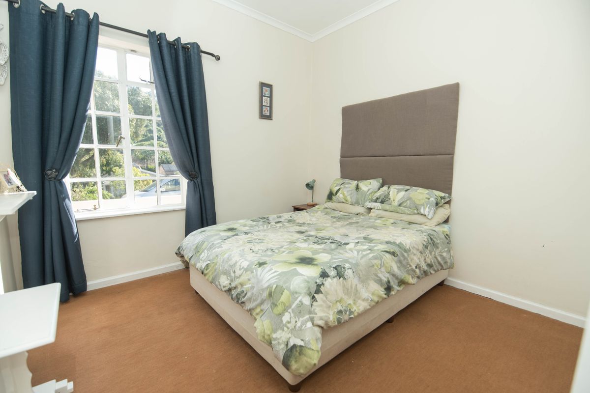 A functional bedroom featuring carpet flooring, a window with curtains, and neutral wall finishes.