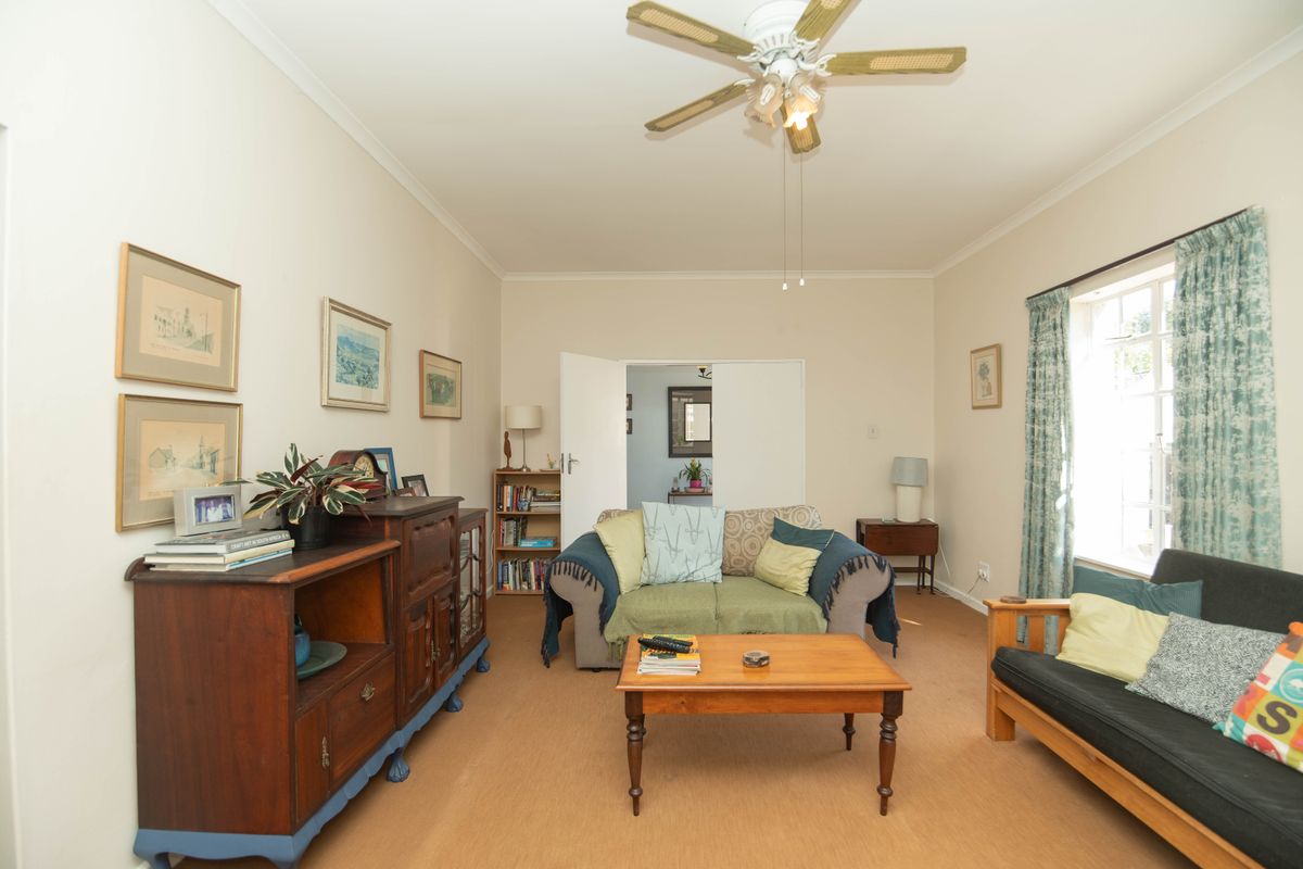 A comfortable living room featuring a ceiling fan, neutral wall finishes, and natural light from the side window.