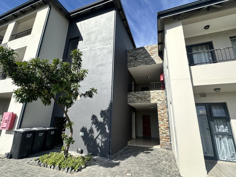 Exterior view of the apartment complex featuring stone cladding accents, paved ground area, and balcony access points.