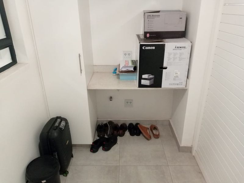 A functional utility nook featuring built-in cabinetry, a stone countertop, and tiled flooring, suitable for a home office or storage area.