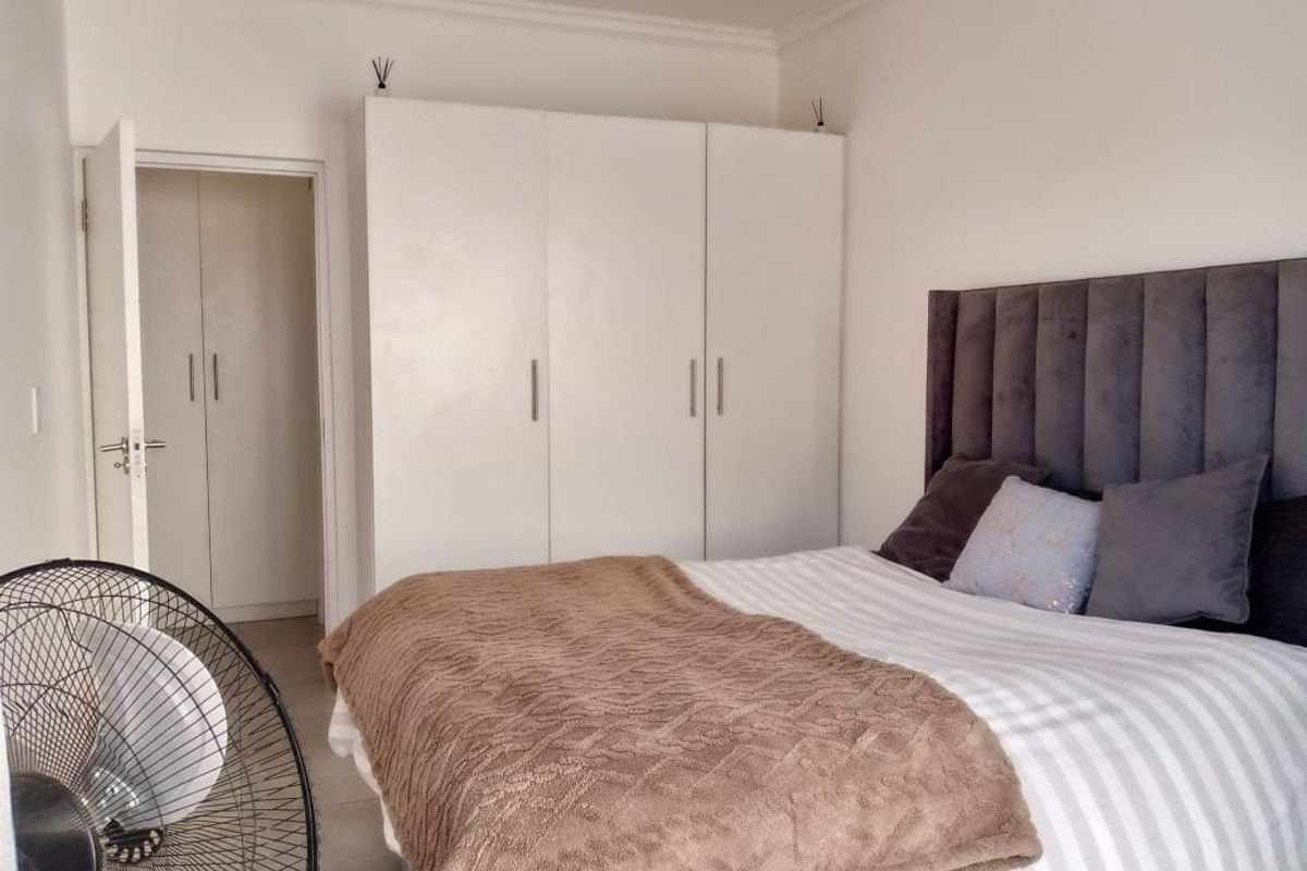 A well-maintained bedroom featuring neutral walls, tiled flooring, and ample built-in cupboard storage space.