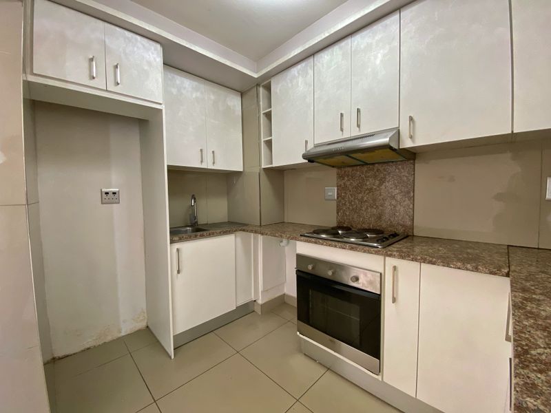 A functional kitchen featuring built-in cabinetry, laminate countertops, a stainless steel sink, and integrated cooking appliances including an oven and hob.