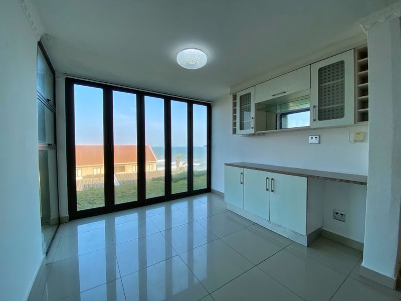 Bright living area featuring tiled flooring, built-in cabinetry, and large bi-fold glass doors offering scenic ocean views.