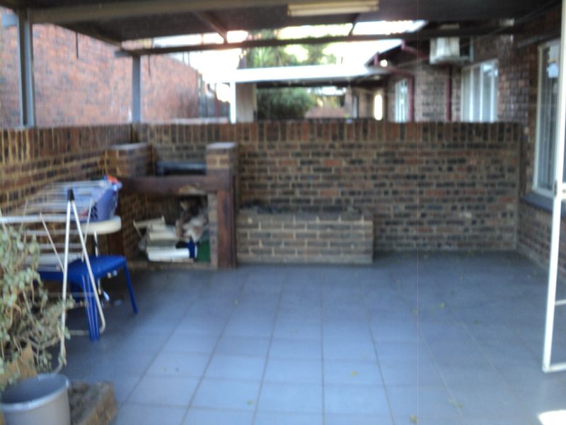 A covered outdoor patio area featuring a built-in brick braai and tiled flooring, providing a functional space for outdoor entertaining.