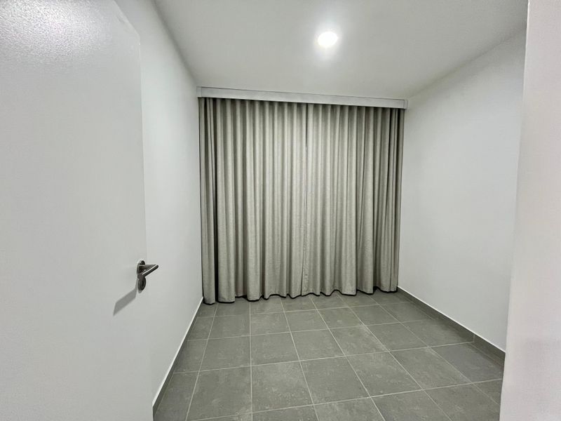 A clean, empty bedroom featuring neutral tiled flooring and recessed ceiling lighting, ready for personalization.