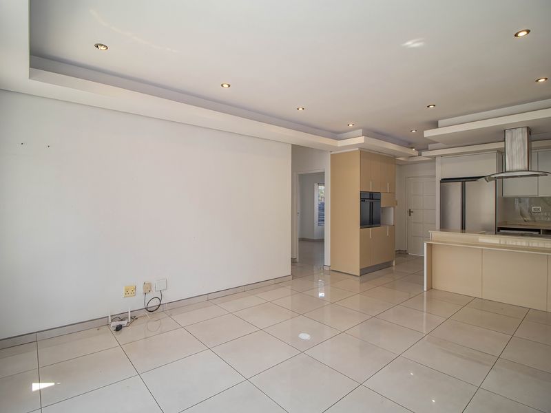 Spacious open-plan living and kitchen area featuring modern tiled flooring, recessed ceiling lighting, and a functional kitchen with built-in appliances and cabinetry.