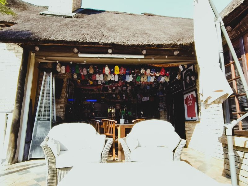 A covered outdoor patio area featuring a traditional thatched roof, brick exterior walls, and tiled flooring, providing a sheltered space for outdoor relaxation.