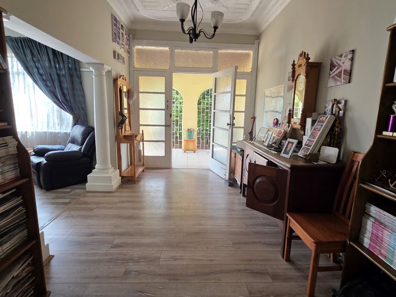 Welcoming entrance hall featuring laminate flooring, decorative ceiling detailing, and a classic column, leading through glass-panelled doors to an outdoor patio area.