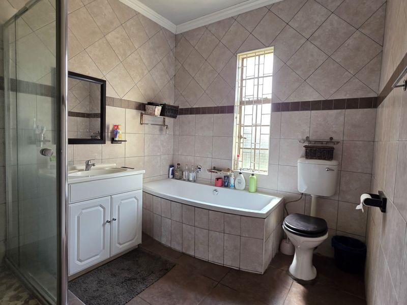A functional bathroom featuring a built-in vanity, bathtub, separate shower enclosure, and tiled wall finishes.