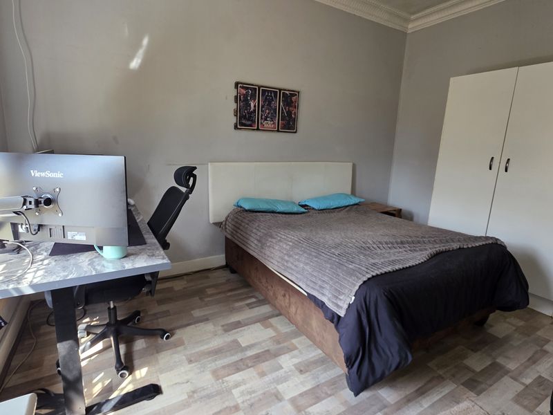A functional bedroom featuring laminate flooring, coving, and a built-in wardrobe, offering a neutral base for potential interior updates.