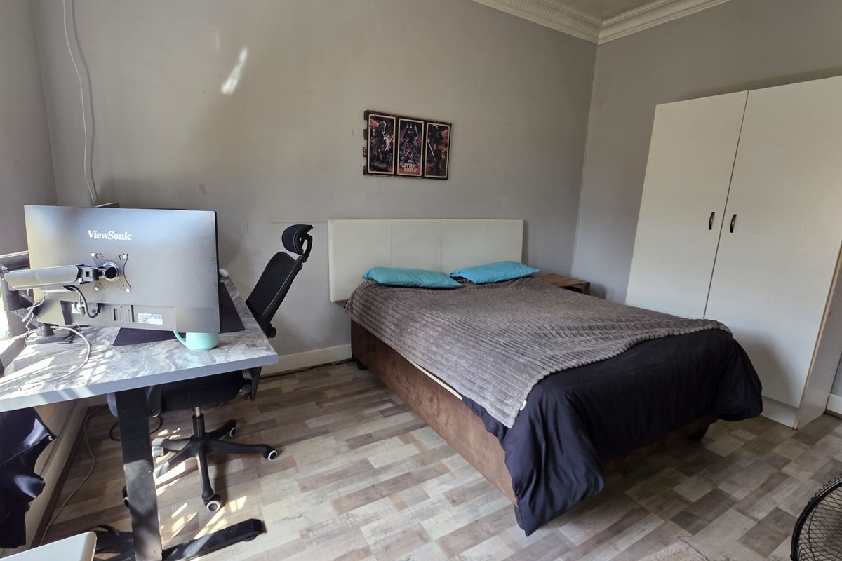 A functional bedroom featuring laminate flooring, coving, and a built-in wardrobe, offering a neutral base for potential interior updates.
