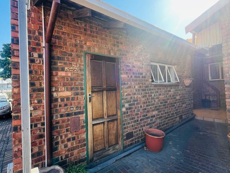A side view of the property featuring a face brick exterior, timber door, and paved walkway.