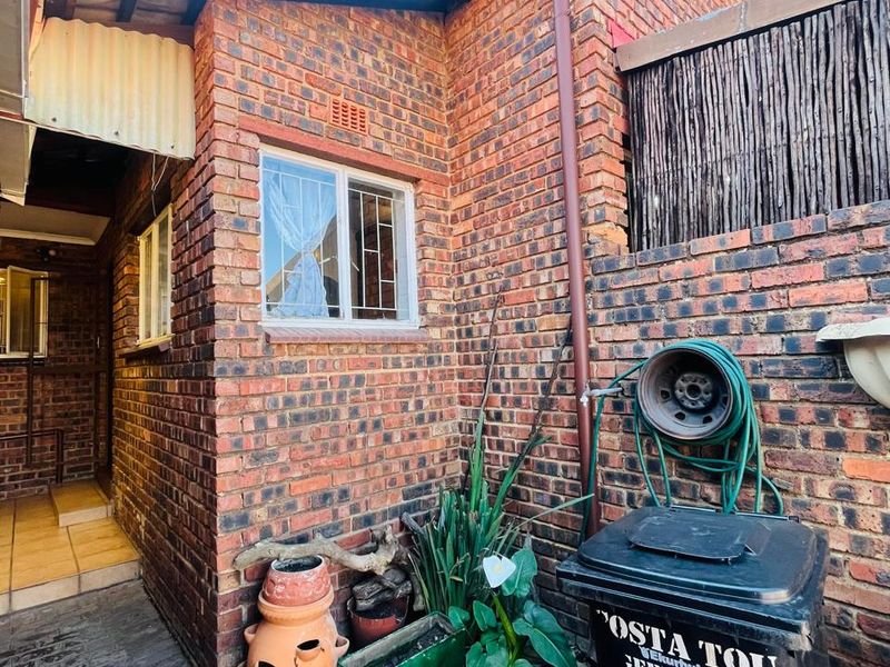 A view of the rear exterior area featuring face brick walls, a paved walkway, and a functional downpipe system.