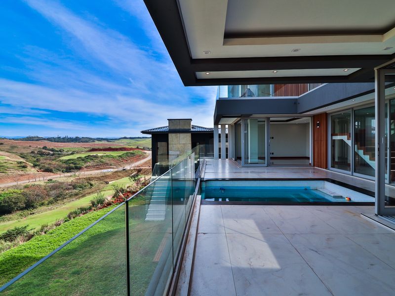 Modern covered patio featuring a built-in plunge pool, glass balustrades, and expansive views over the surrounding landscape.