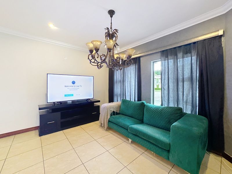 A living room featuring tiled flooring, a decorative chandelier, and cove cornicing, providing a functional space for relaxation.