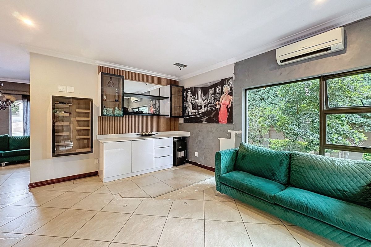 Living room featuring a built-in bar area, tiled flooring, and wall-mounted air conditioning, with some areas requiring finishing touches to walls and flooring.