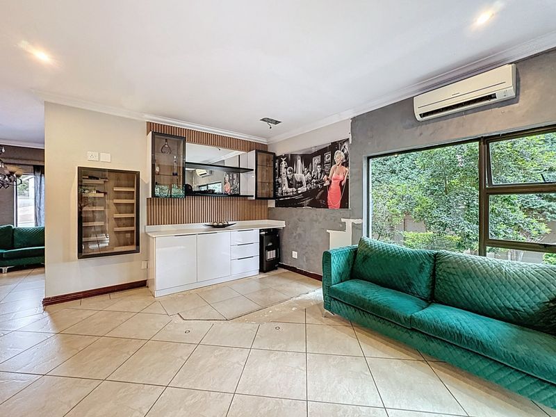 Living room featuring a built-in bar area, tiled flooring, and wall-mounted air conditioning, with some areas requiring finishing touches to walls and flooring.