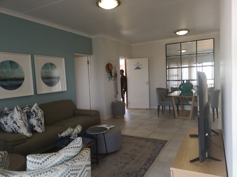 Open plan living and dining area featuring tiled flooring, neutral wall finishes, and a decorative mirrored feature wall.