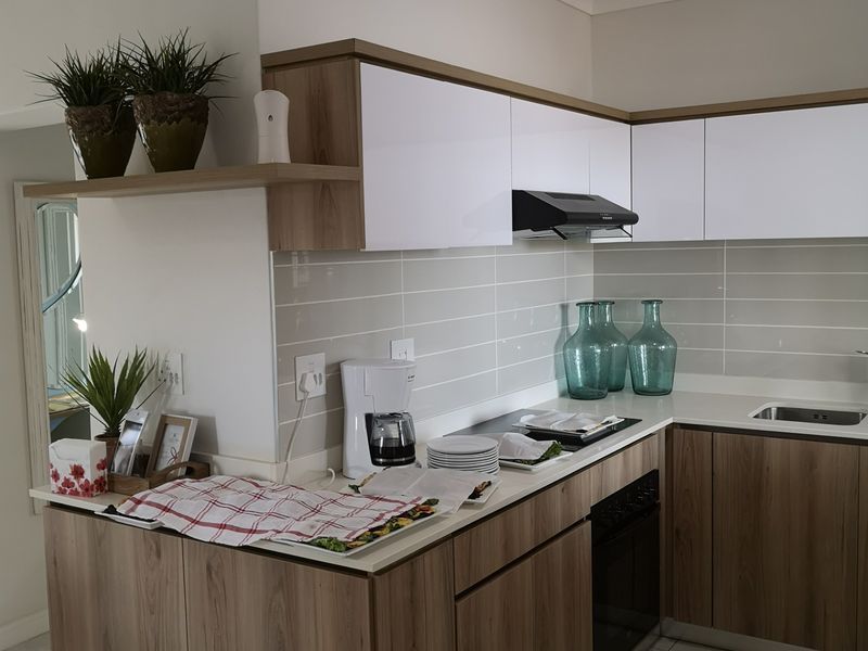 Modern kitchen featuring wood-grain cabinetry, white upper cabinets, subway tile backsplash, and integrated appliances, offering a clean and functional cooking space.
