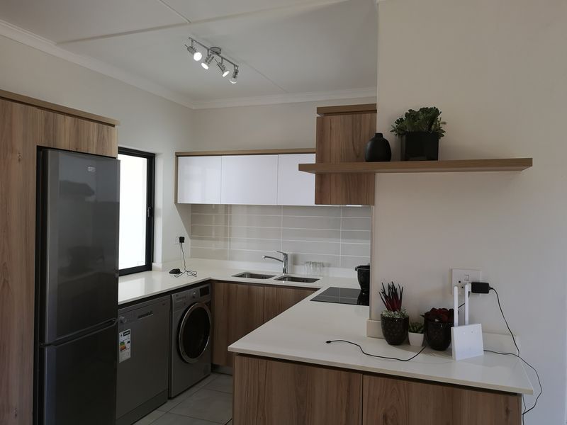Modern kitchen featuring wood-grain cabinetry, white stone countertops, tiled backsplash, and integrated appliances, offering a clean and functional cooking space.