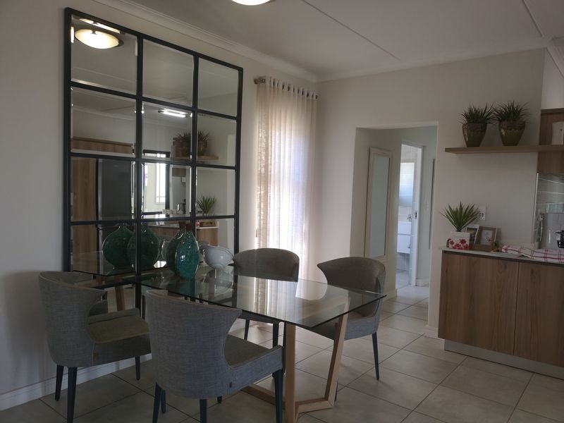 A well-maintained dining area featuring tiled flooring, a decorative grid-style wall mirror, and built-in cabinetry, providing a functional and modern living space.
