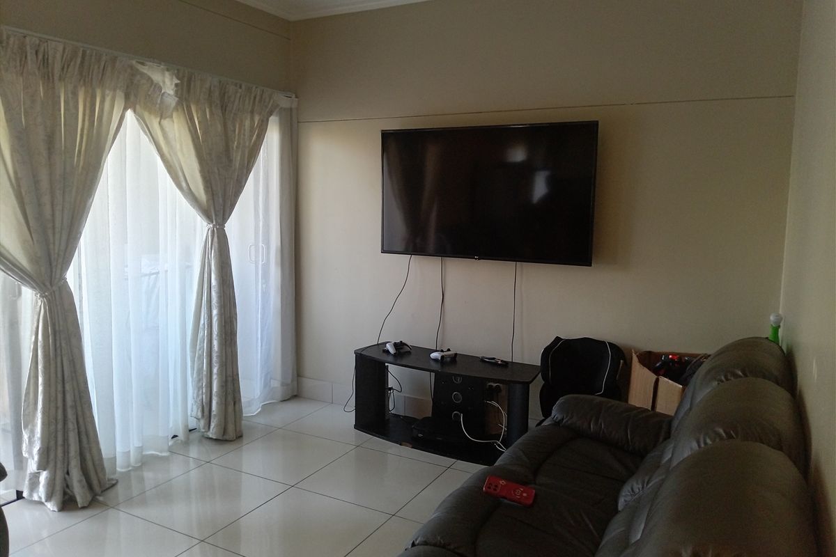 A living room featuring neutral wall tones, tiled flooring, and a sliding glass door providing access to an outdoor area.