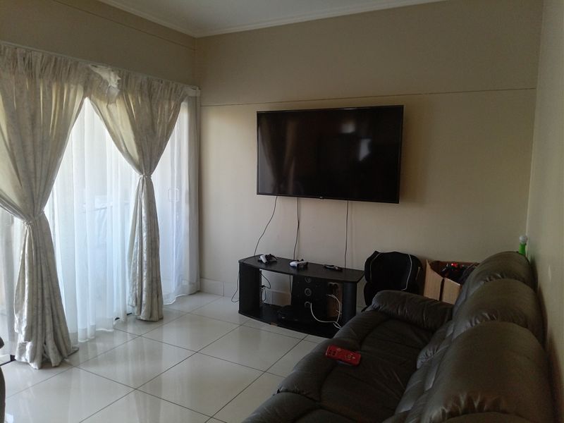 A living room featuring neutral wall tones, tiled flooring, and a sliding glass door providing access to an outdoor area.