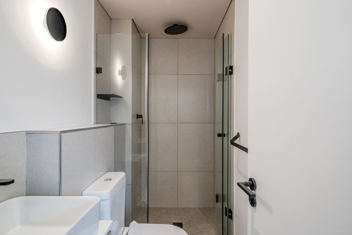 Modern bathroom featuring a walk-in shower with a rain shower head, glass enclosure, vessel sink, and contemporary matte black fixtures.