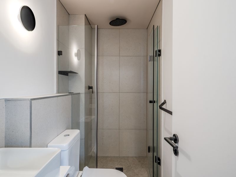 Modern bathroom featuring a walk-in shower with a rain shower head, glass enclosure, vessel sink, and contemporary matte black fixtures.