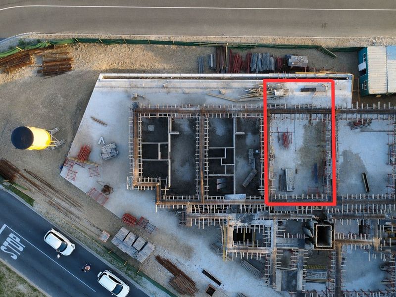 Aerial view of a residential apartment construction site showing the concrete foundation and structural rebar layout.