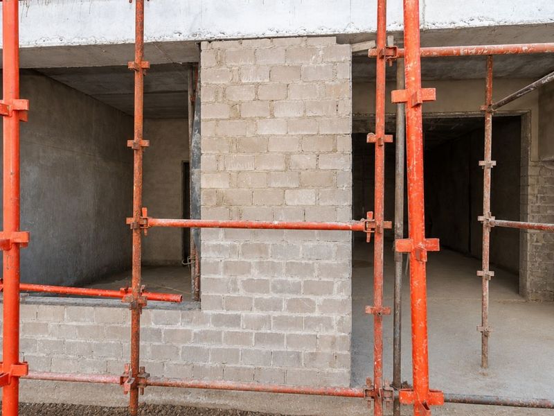 Exterior view of an apartment building under construction, featuring exposed concrete block walls and structural scaffolding.