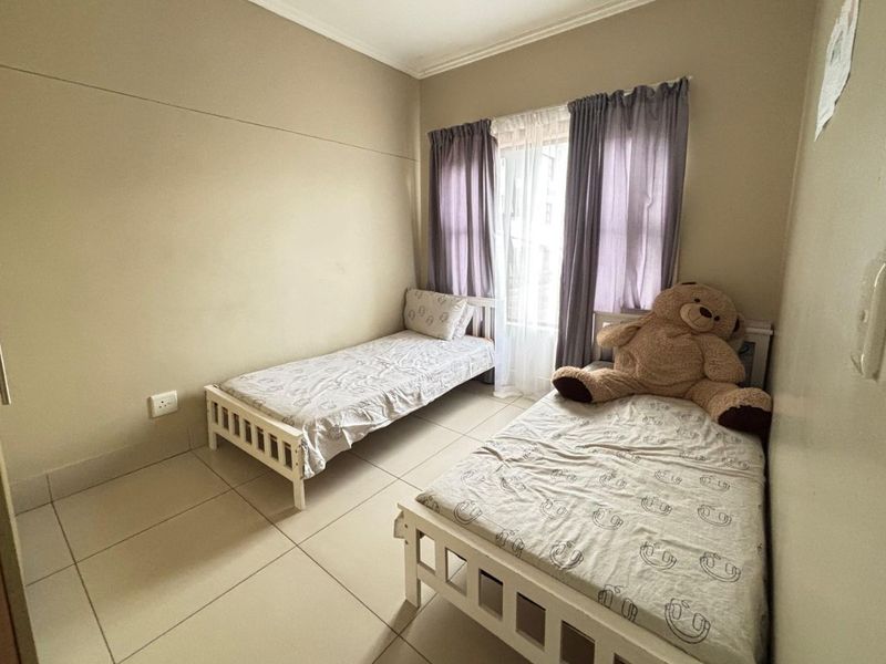 A functional bedroom featuring neutral wall paint, tiled flooring, and a window with installed curtain rails.