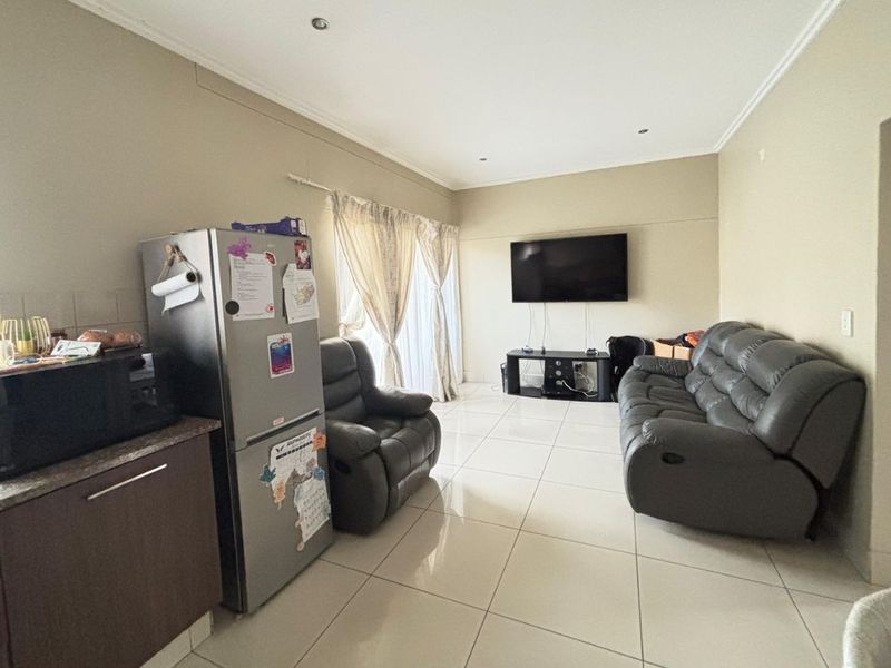 Open plan living area featuring tiled floors, recessed lighting, and a compact kitchen section with granite countertops, leading to a sliding door.