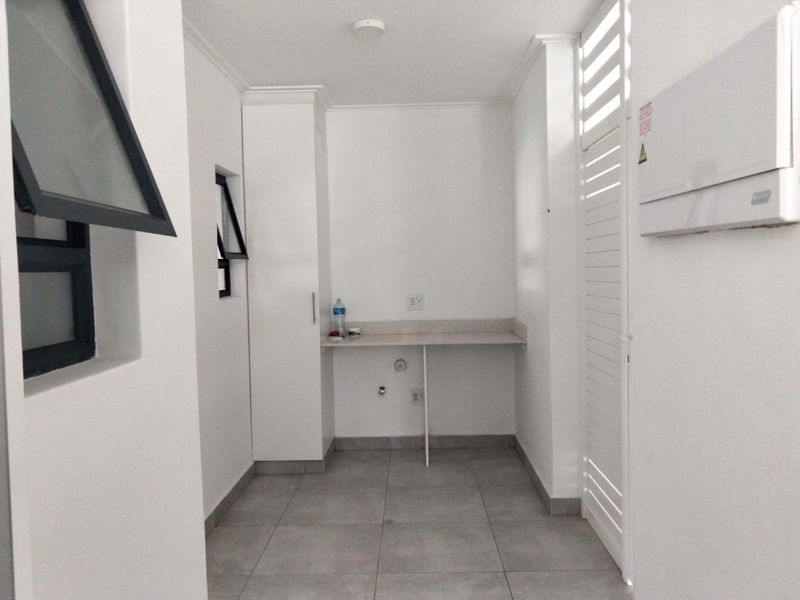 A clean, functional laundry area featuring tiled floors, built-in cabinetry, a stone countertop, and dedicated plumbing connections for appliances.