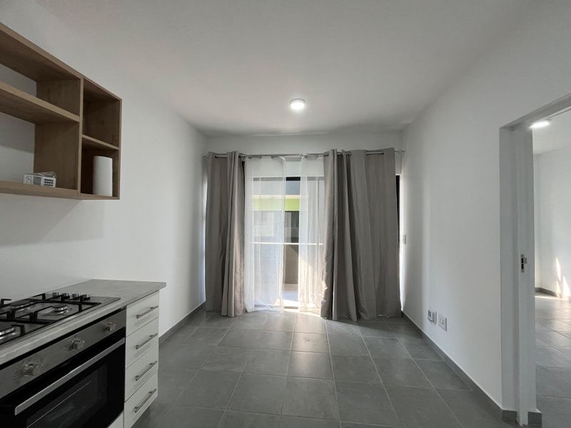 Modern kitchen featuring tiled flooring, built-in oven, gas hob, and open shelving, with direct access to a balcony through a sliding glass door.
