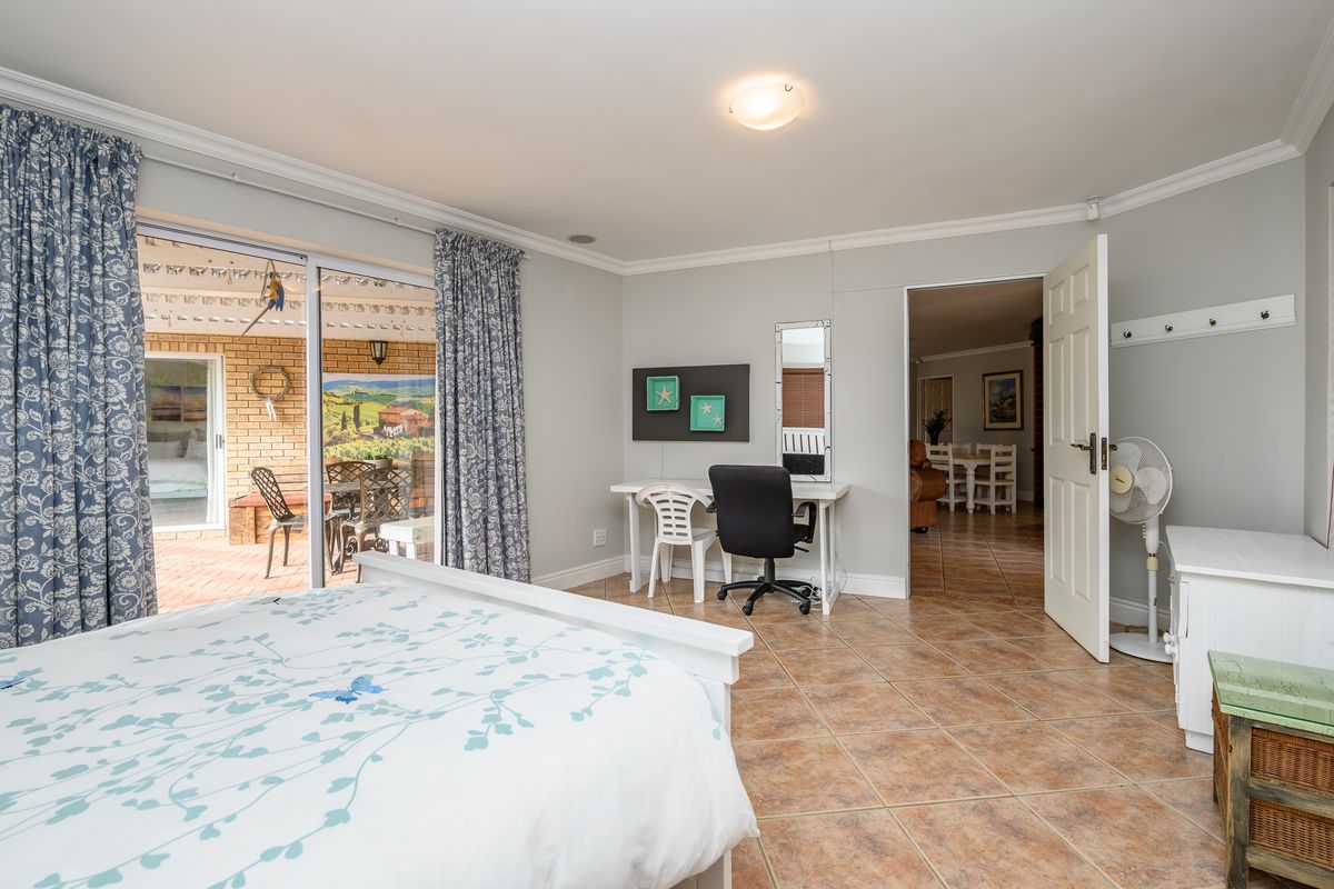Spacious bedroom featuring ceramic tile flooring, cove cornicing, and a sliding glass door providing direct access to the outdoor patio area.